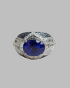 18kt White Gold Ring Showcasing Deep Blue Tanzanite, accented with Shimmering Diamonds and Vibrant Blue Sapphires.
